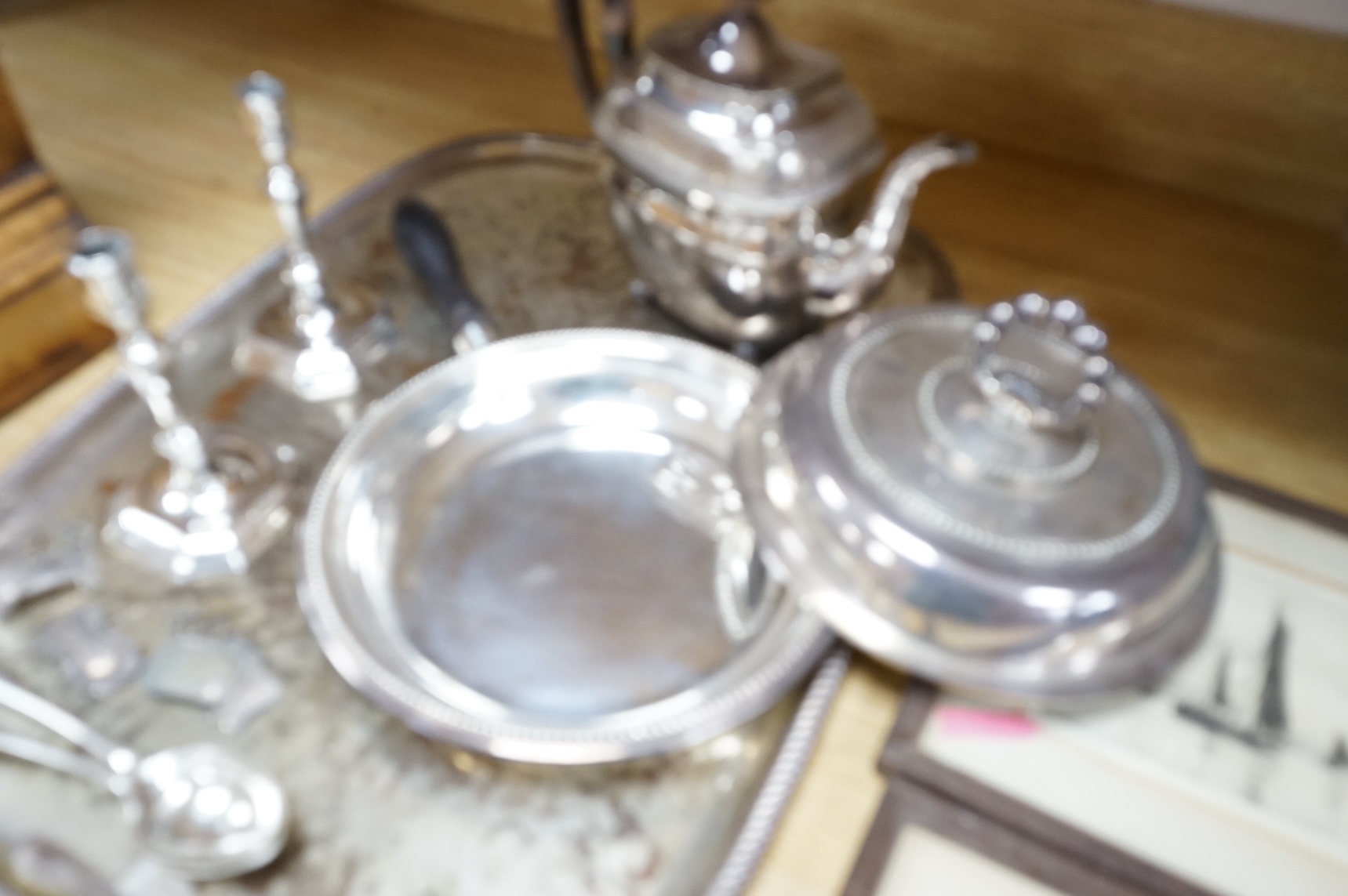 A pair of white metal candlesticks, a silver plated teapot circular tureen and cover spoons and forks and four spirit labels and large tray. Tray 73cm wide